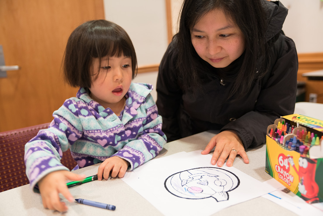 A mother and her daughter spend time at a coloring themed passport station to work on the daughter’s fine motor skills.