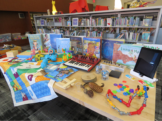 A library display of picturebook biographies, toys, and games.