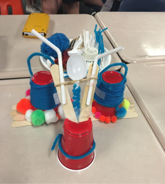 A collection of materials used to engineer ther solutions, including plastic cups, pipe cleaners, straws, and tongue depressers.