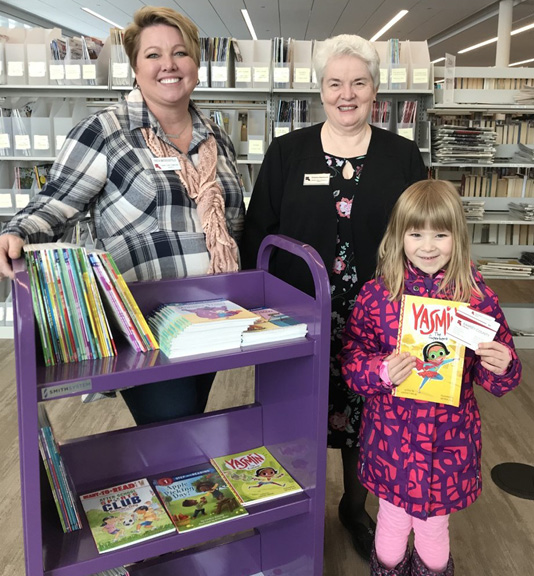 Ramsey County Board of Commissioners Trista MatasCastillo and Victoria Reinhardt pose with kindergartener Laura and her new library card.