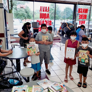 Children receive books as part of national Summer Learning in Your Laundromat at Blue Kangaroo Laundromat in Chicago.