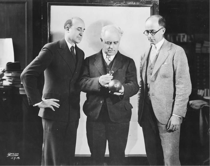 Carl Cannon (left), president of the New York State Library Association, Frederic G. Melcher (right), and Charles J. Finger, winner of the 1924 Newbery Medal for Courageous Companions, a story based on Magellan’s voyage around the world. The photograph was taken in the Circulating Room of the New York Public Library.
