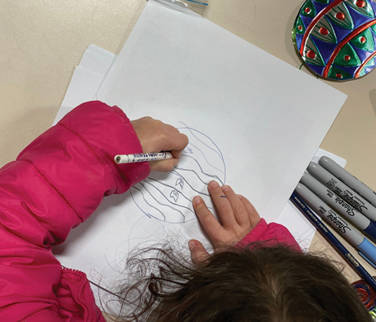 Child sketching the design for a tin ornament