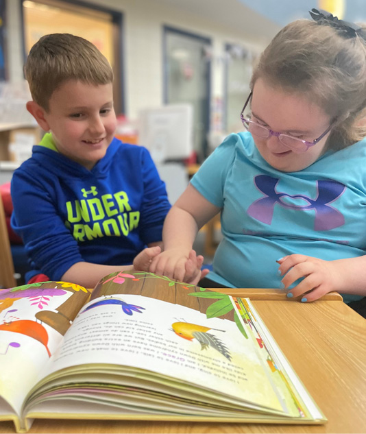 Two children reading a book together in a library