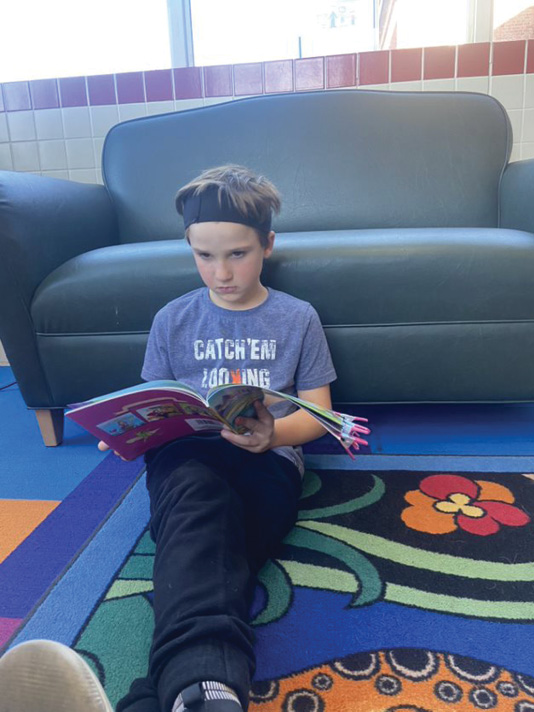 Just chillin’ out with a book. A boy reads a book while sitting on the carpet.