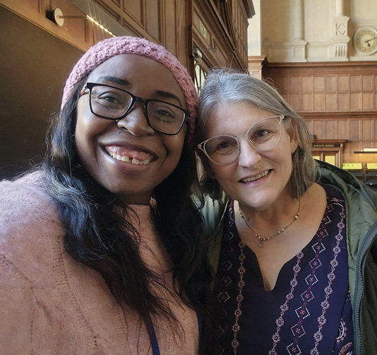 Caroline  Simuchimba and Betsy Diamant-Cohen posing together at the entrance to Examination Hall.