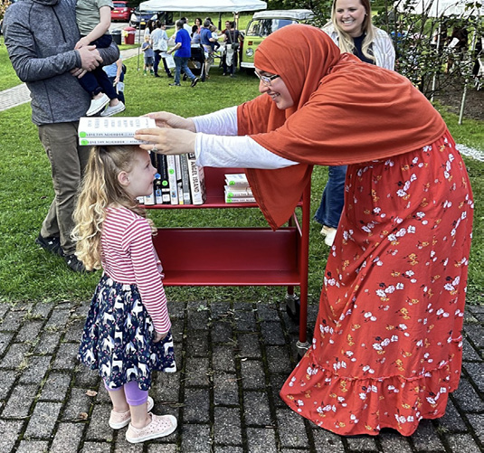 Participants at the Library Expedition. A woman balances two books on the head of a child.