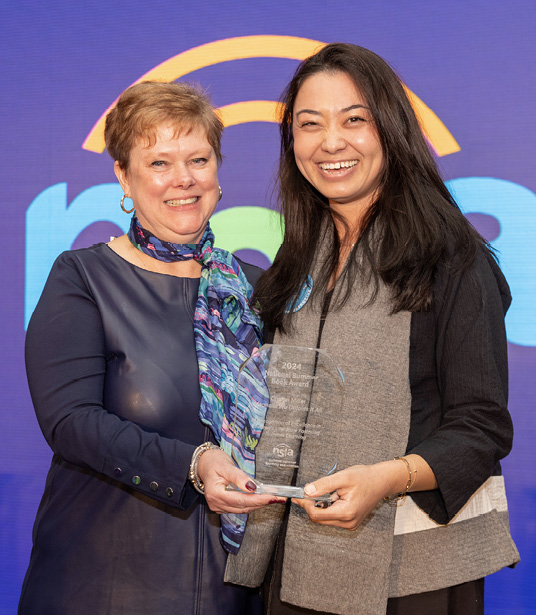 Author Chanel Miller (r) receives the 2024 National Summer Book Award from Elizabeth McChesney at the 2024 Summit of the National Summer Learning Association.